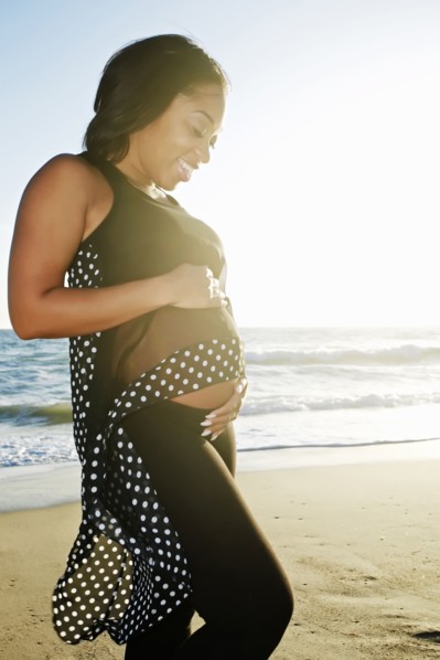Pregnant woman holding her belly on beach
