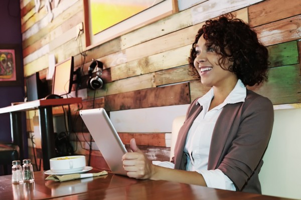 Mixed race woman using tablet computer in cafe