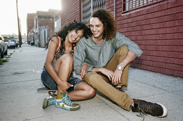 Couple sitting on skateboard on city street