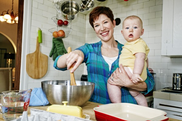 Caucasian mother cooking with baby in kitchen