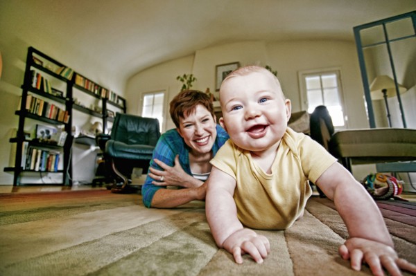 Caucasian mother and baby playing on living room floor