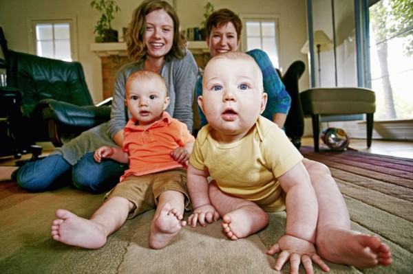 Caucasian mothers and babies sitting on living room floor
