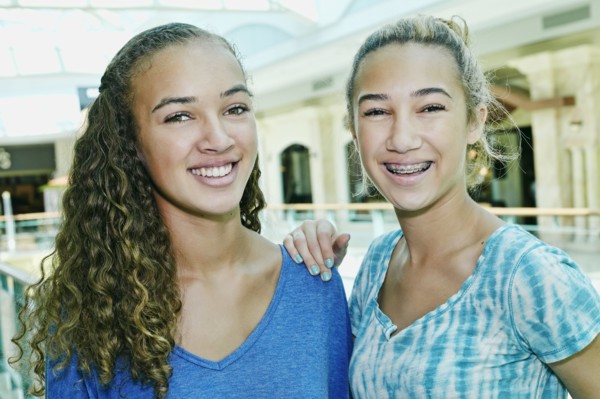 Mixed race teenage girls smiling at shopping mall