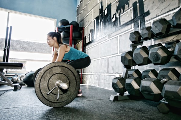 Mixed race woman lifting weights in gym