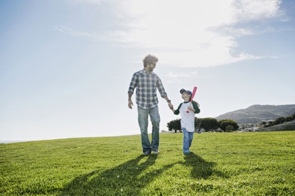 Father and daughter walking in grassy field