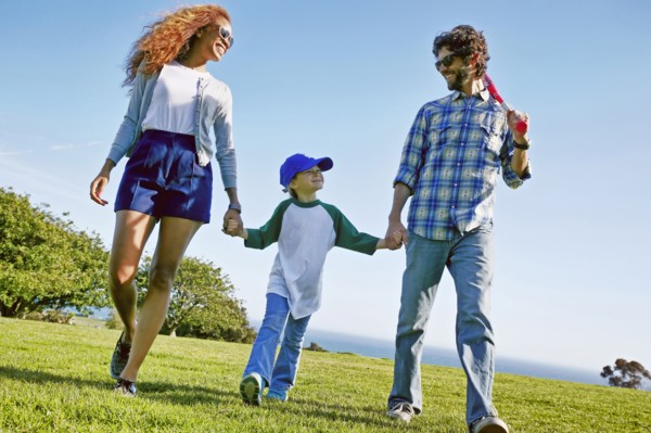 Parents and daughter walking in grassy field