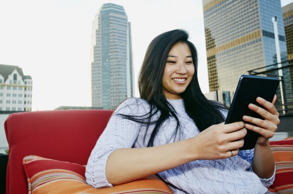 Chinese woman using digital tablet on urban rooftop