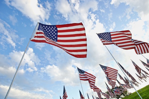 Low angle view of American flags under blue sky