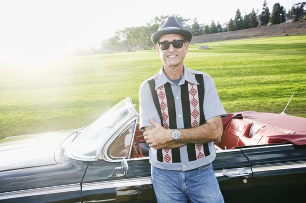 Mixed race man smiling near classic convertible