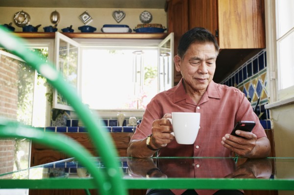 Filipino man using cell phone in kitchen