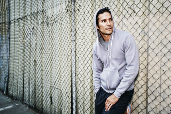 Mixed race man leaning on chain link fence