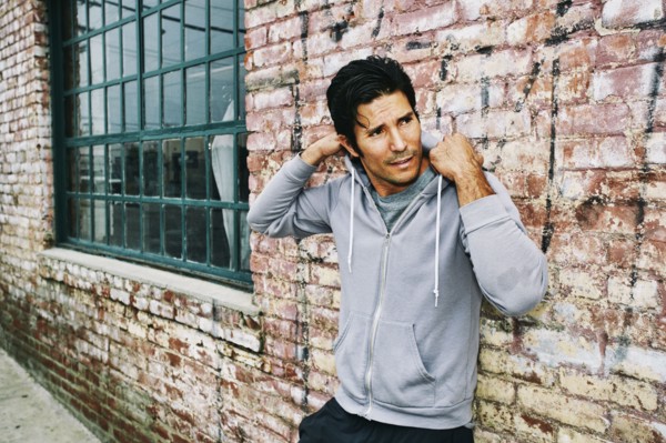 Mixed race man leaning on brick building