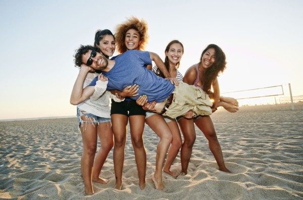 Smiling friends posing together on beach