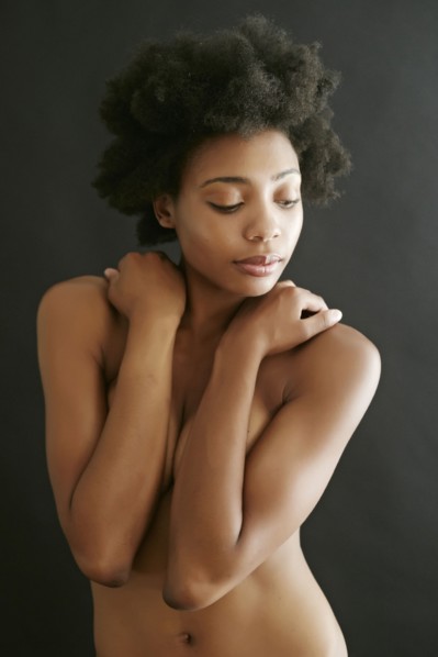 Nude black woman covering her breasts