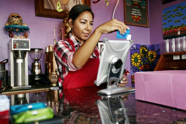 Hispanic barista using digital tablet register in coffee shop