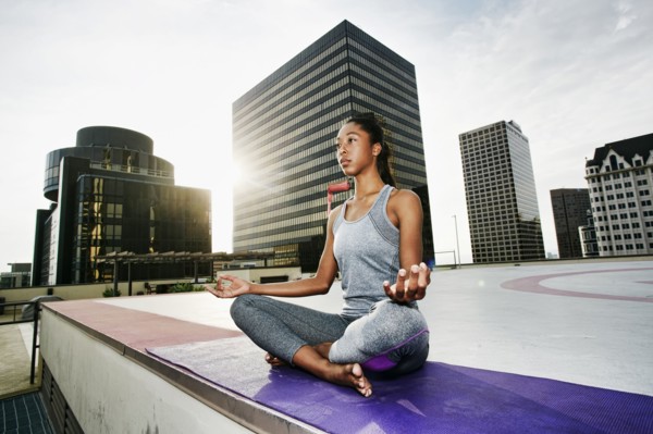 African American woman meditating on urban rooftop