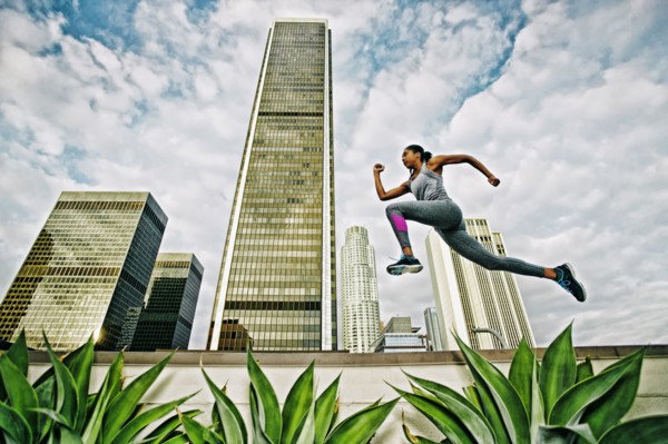 African American woman leaping on urban rooftop