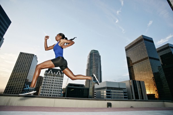 African American woman leaping on urban rooftop
