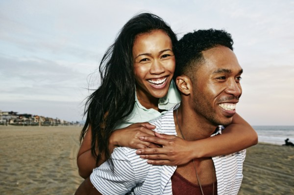 Man carrying girlfriend piggyback on beach