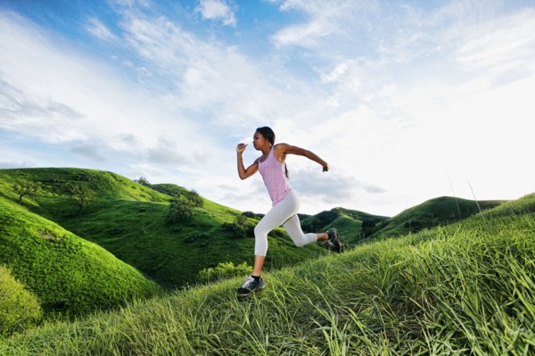 Black athlete running on rural hillside