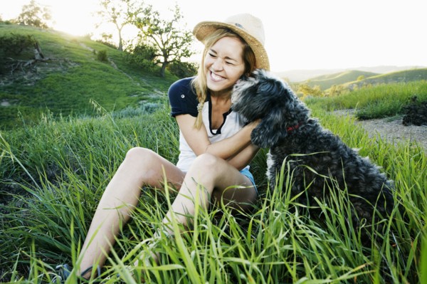 Caucasian woman petting dog in field