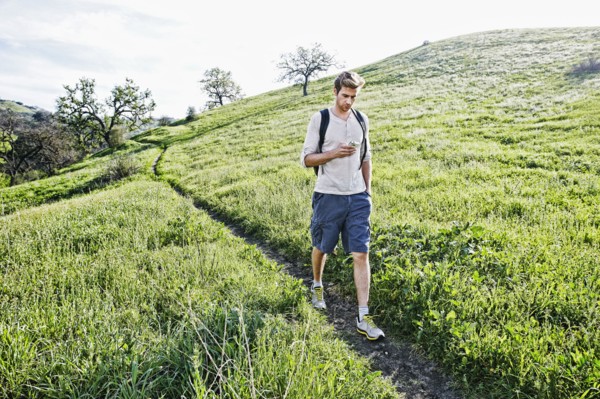 Caucasian man using cell phone on dirt path