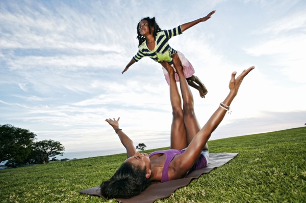 Mother balancing daughter on legs in park