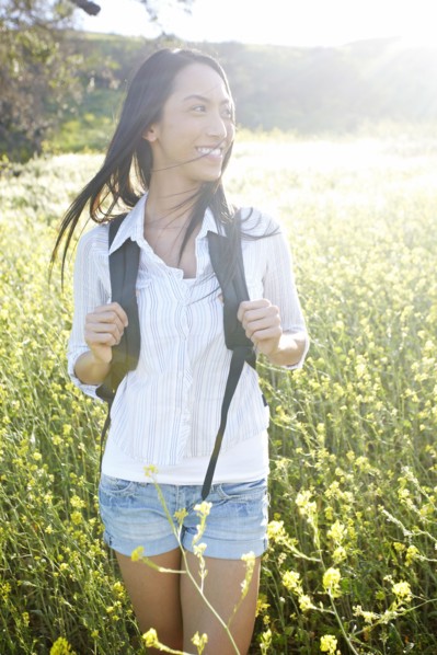 Mixed race woman carrying backpack in field