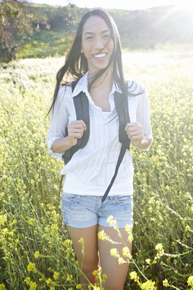 Mixed race woman carrying backpack in field