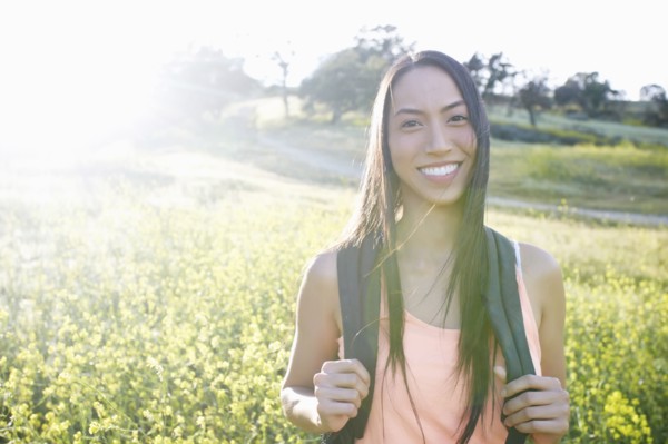 Mixed race woman carrying backpack in field