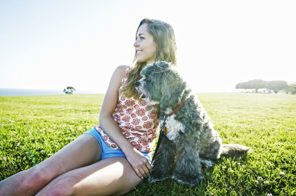 Caucasian woman sitting in field with dog