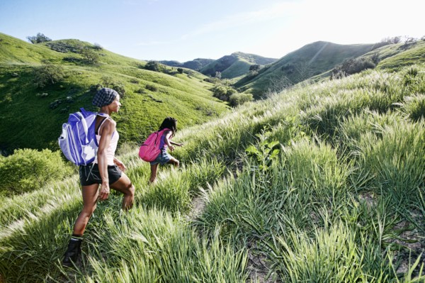 Black mother and daughter walking on rural hillside