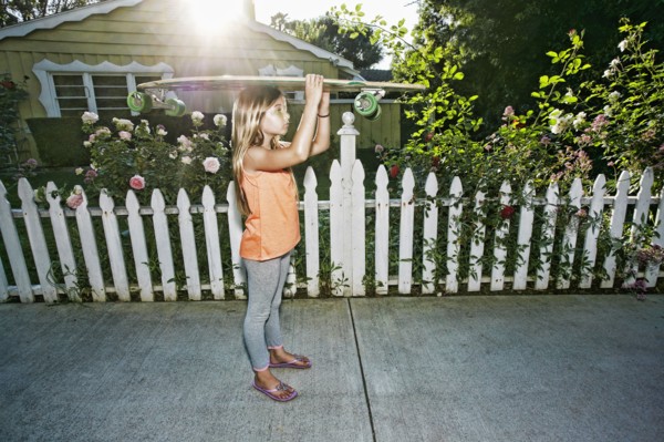 Caucasian girl carrying skateboard on sidewalk