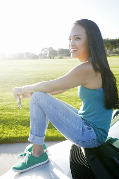 Asian woman sitting on car
