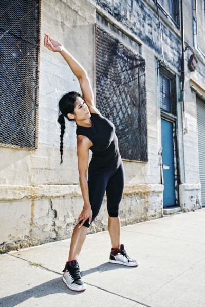 Mixed race woman stretching on sidewalk