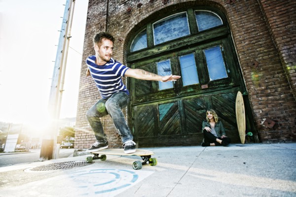 Caucasian man riding skateboard on sidewalk
