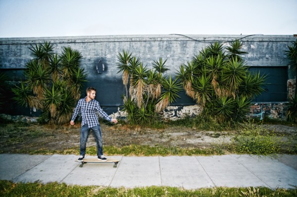 Caucasian man riding skateboard on sidewalk