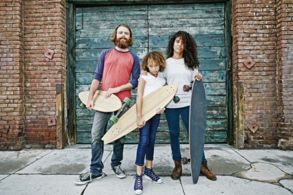 Family holding skateboards on sidewalk