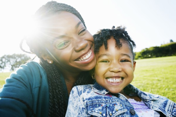Black mother and daughter smiling outdoors