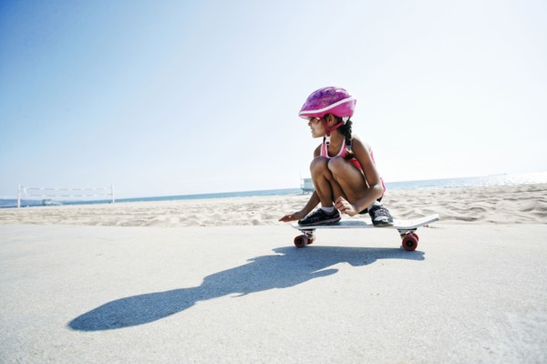 Mixed race girl riding skateboard at beach