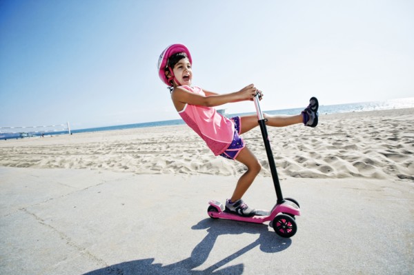 Girl riding scooter at beach