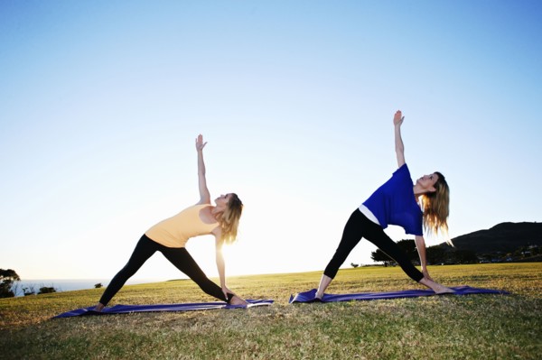 Caucasian women practicing yoga in field