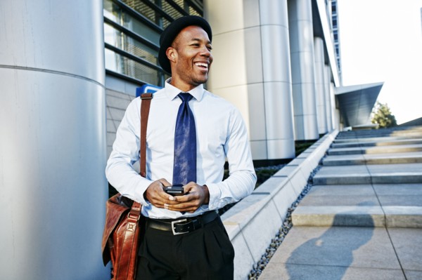 Black businessman using cell phone outside office building
