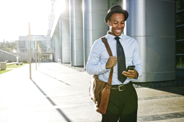 Black businessman using cell phone outside office building