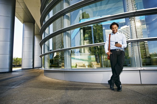 Black businessman using cell phone outside office building