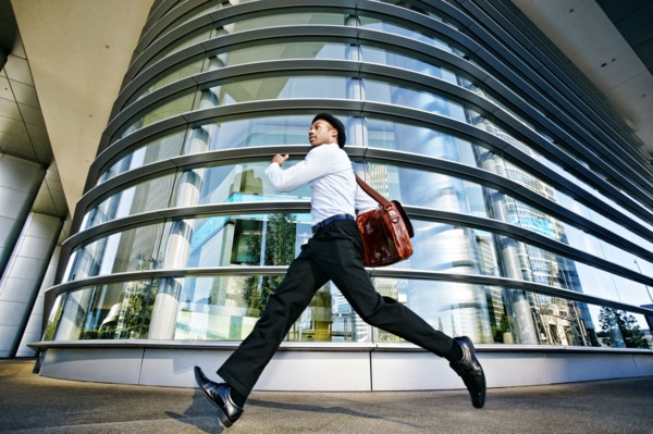 Black businessman running outside office building