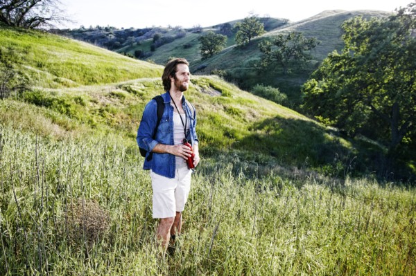 Caucasian hiker standing in grass on mountain holding water bottle