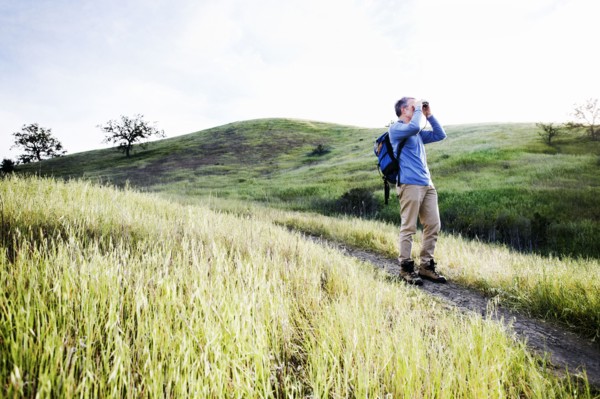 Caucasian man using binoculars on dirt path