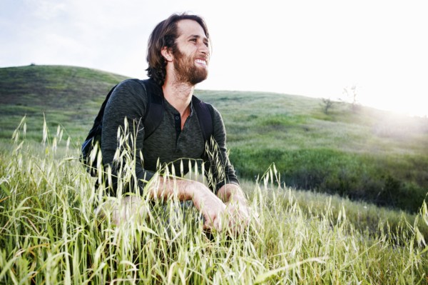 Caucasian hiker crouching in grass on mountain