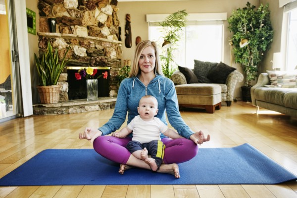 Mother meditating on exercise mat with baby in lap